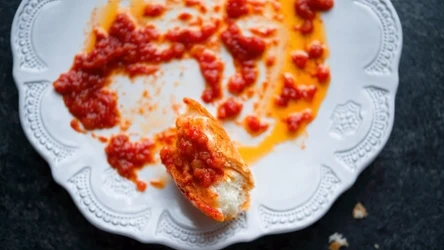 biały talerz z resztkami sosu pomidorowego i kawałkiem chleba do "wylizania" talerza