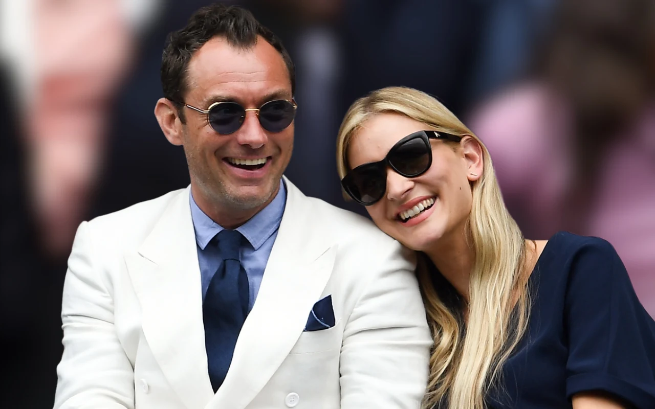 Jude Law i Phillipa Coan uśmiechnięci, w ciemnych okularach, siedzą na trybunach