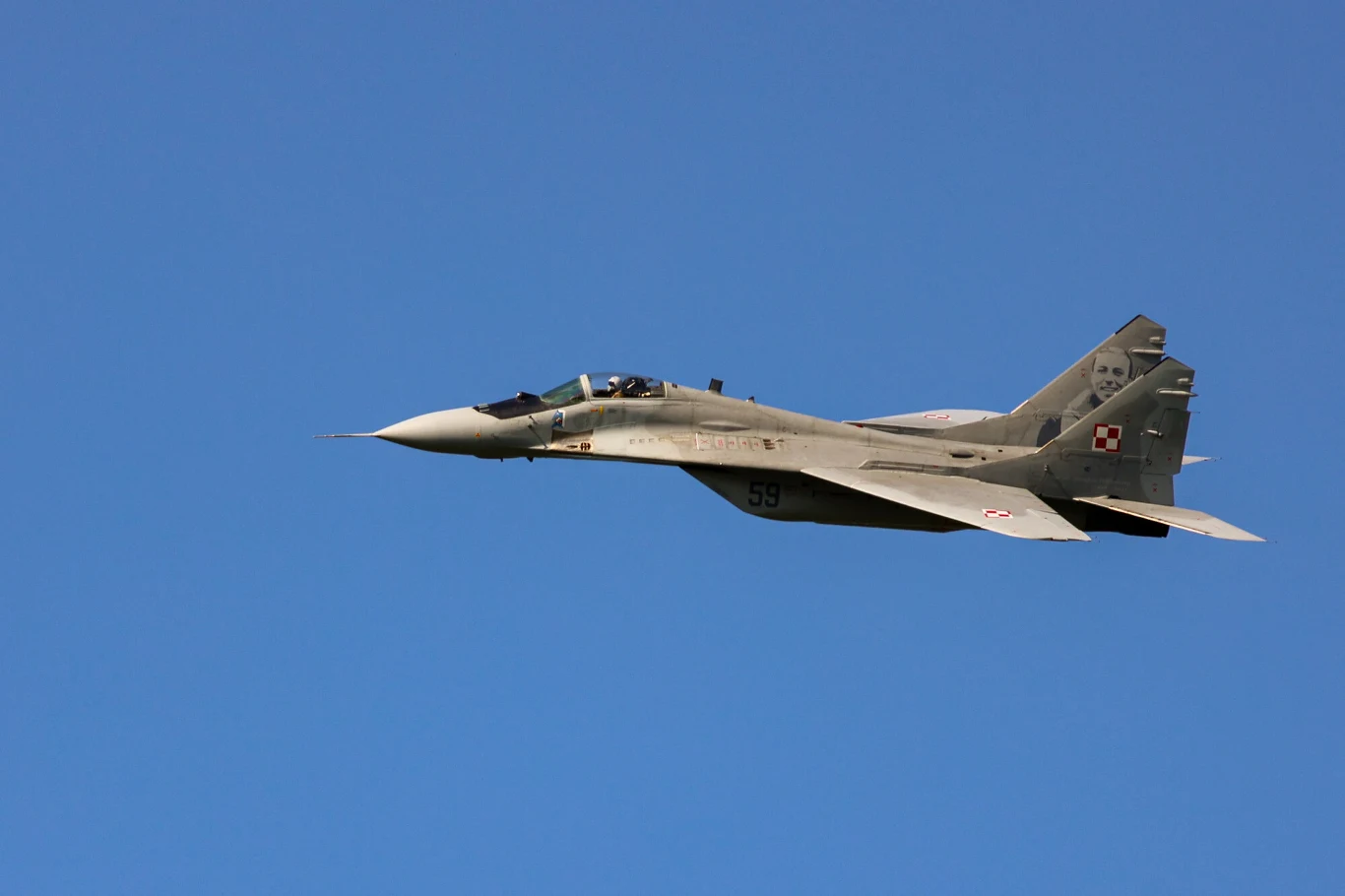 Polskie MiG-29 trafią na Ukrainę? Szef MON: Taka jest nasza intencja Wojskowy odrzutowiec MiG-29 z polskimi oznaczeniami lotnictwa wojskowego na tle jednolitego, błękitnego nieba.
