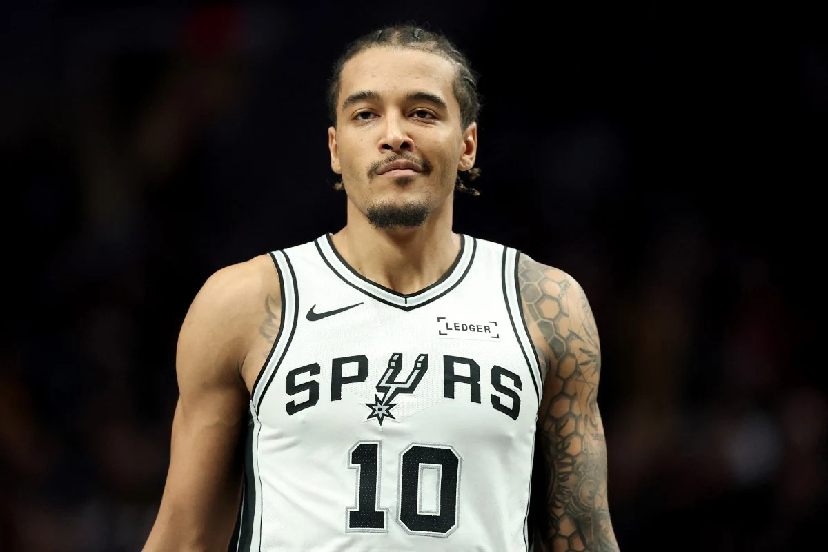 Jeremy Sochan spędził cały mecz na ławce rezerwowych Koszykarz drużyny San Antonio Spurs w białym stroju z numerem 10 stoi na boisku podczas meczu, z widocznymi tatuażami na lewym ramieniu.