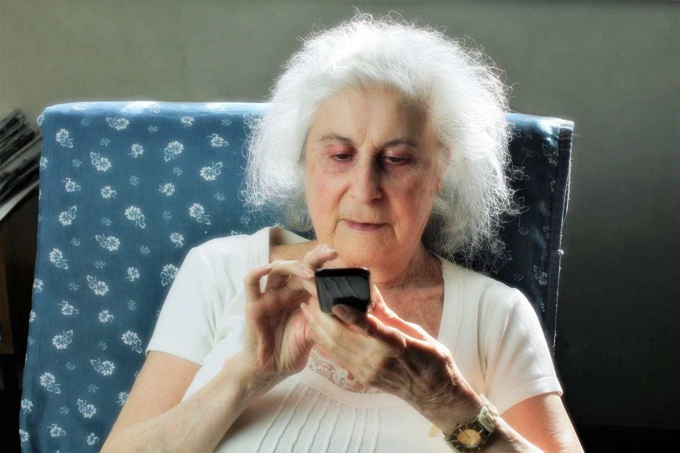 Energię tego dnia odczuje trójka wybrańców. Już mogą zaznaczyć tę datę Starsza kobieta z siwymi włosami siedzi na fotelu z niebieskim pokrowcem w białe wzory i wpatruje się w czarny telefon komórkowy trzymany w dłoniach.