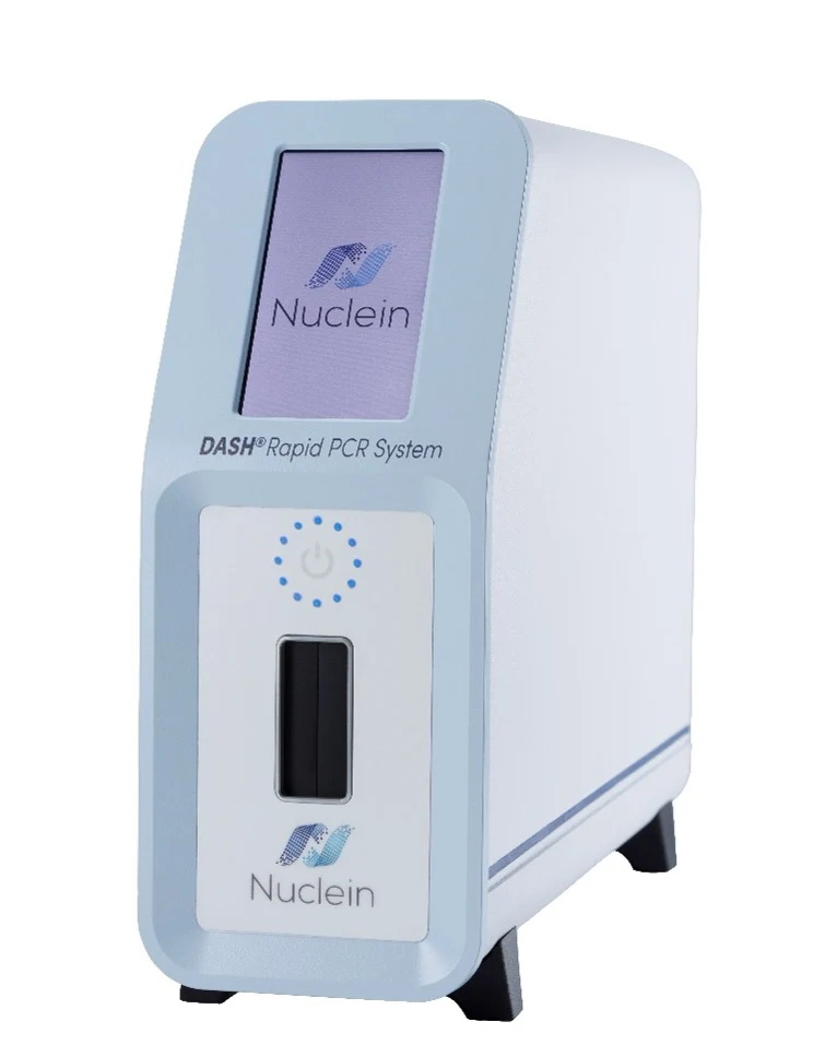 Platforma PCR DASH® Nowoczesny system PCR typu DASH Rapid marki Nuclein, z panelem sterowania oraz ekranem wyświetlającym logo firmy, obudowa w biało-niebieskich barwach, kompaktowa konstrukcja dostosowana do diagnostyki laboratoryjnej.