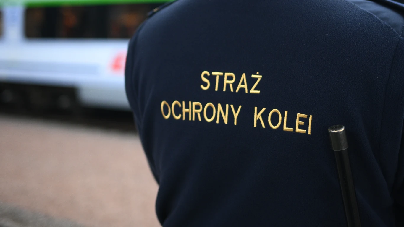 Incydent na bydgoskiej kolei. Zatrzymano 41-latka z Gruzji (zdj. ilustracyjne) Mundur z napisem Straż Ochrony Kolei, fragment sylwetki funkcjonariusza oraz widoczny w tle rozmyty pociąg.