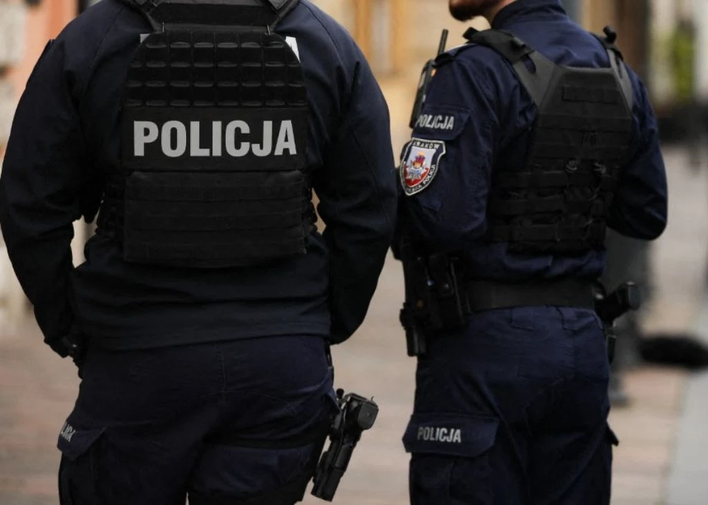 Skarga na Polskę do TSUE. Chodzi o dostęp do adwokata na wczesnym etapie śledztw Dwóch policjantów ubranych w granatowe mundury i kamizelki kuloodporne, widocznych z tyłu podczas patrolowania miejskiej ulicy, na plecach jeden z nich ma napis 'Policja', obaj wyposażeni w sprzęt służbowy.