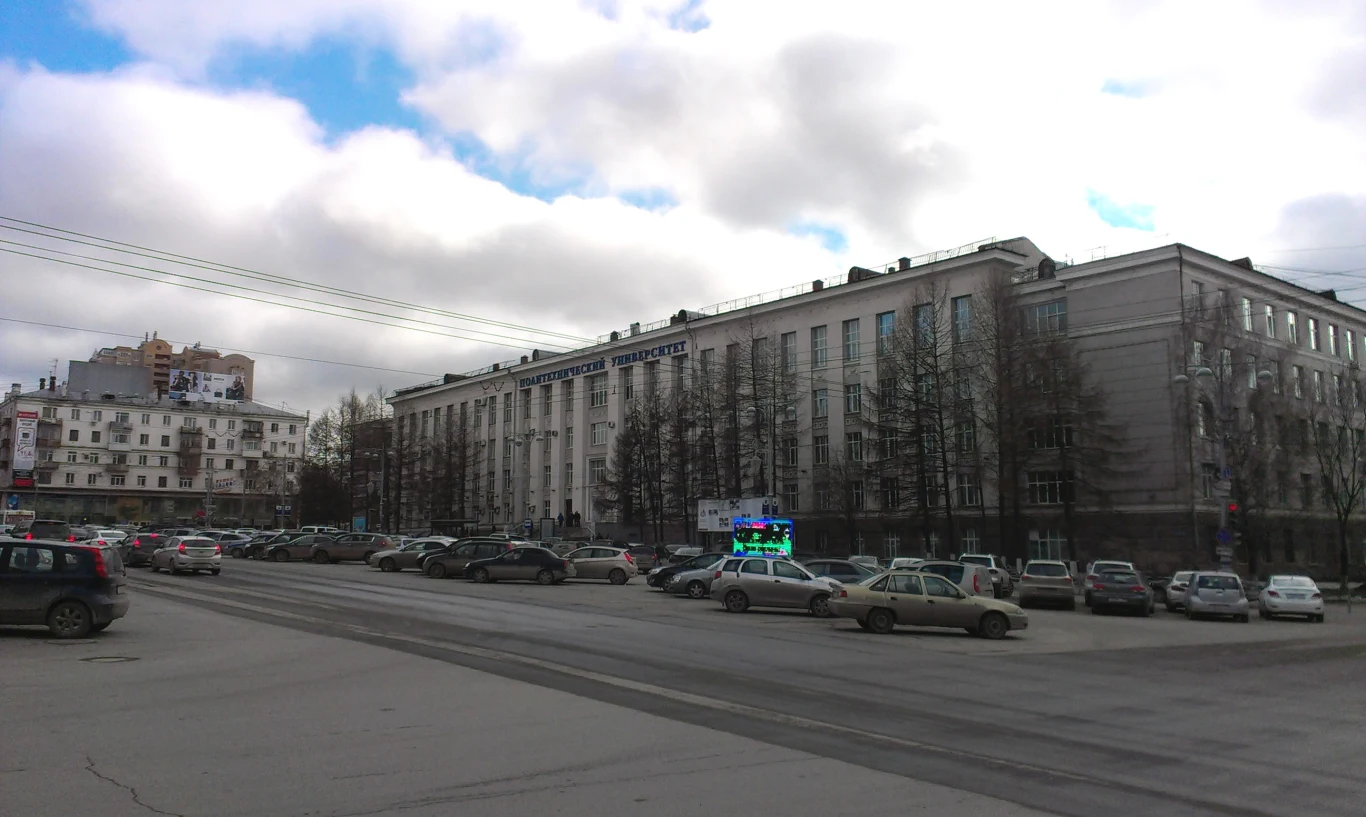 W laboratorium Permskiego Narodowego Politechniki Badawczej (PNRPU) doszło do eksplozji Głównym elementem sceny jest rozległy budynek o klasycznej architekturze z dużą liczbą okien, otoczony przez parkowane samochody oraz miejską infrastrukturę. Przed budynkiem znajduje się szeroka ulica, a po lewej stronie widoczne są inne zabudowania mi...