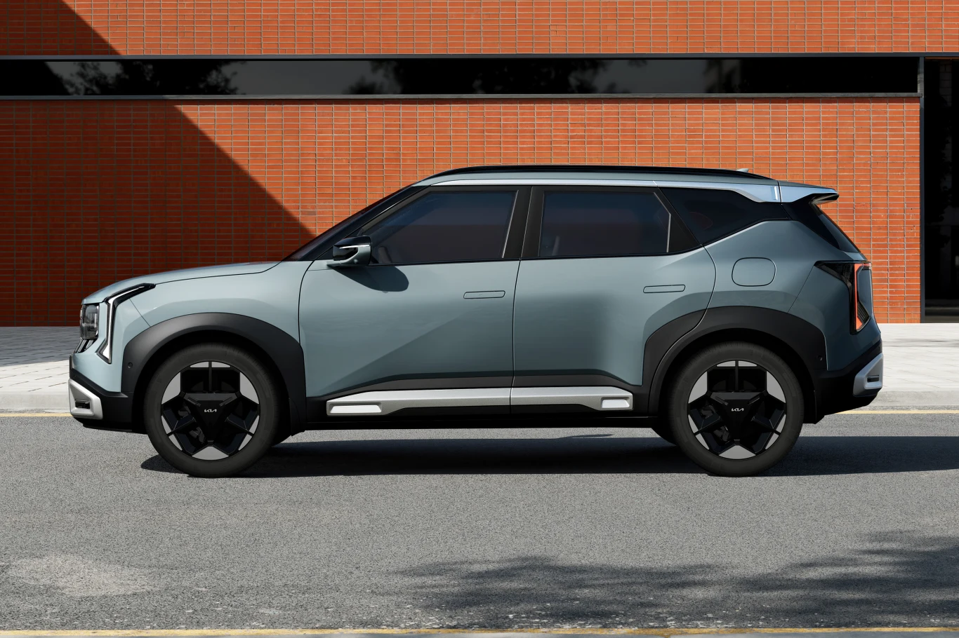 Przy długości 4430 mm, czyli jak w Niro, Seltos ma oferować przestronniejsze wnętrze Szary nowoczesny SUV zaparkowany na ulicy, stojący na tle ceglanego budynku z poziomym czarnym pasem okien. Reflektory i felgi o geometrycznych kształtach nadają samochodowi dynamiczny, futurystyczny wygląd.