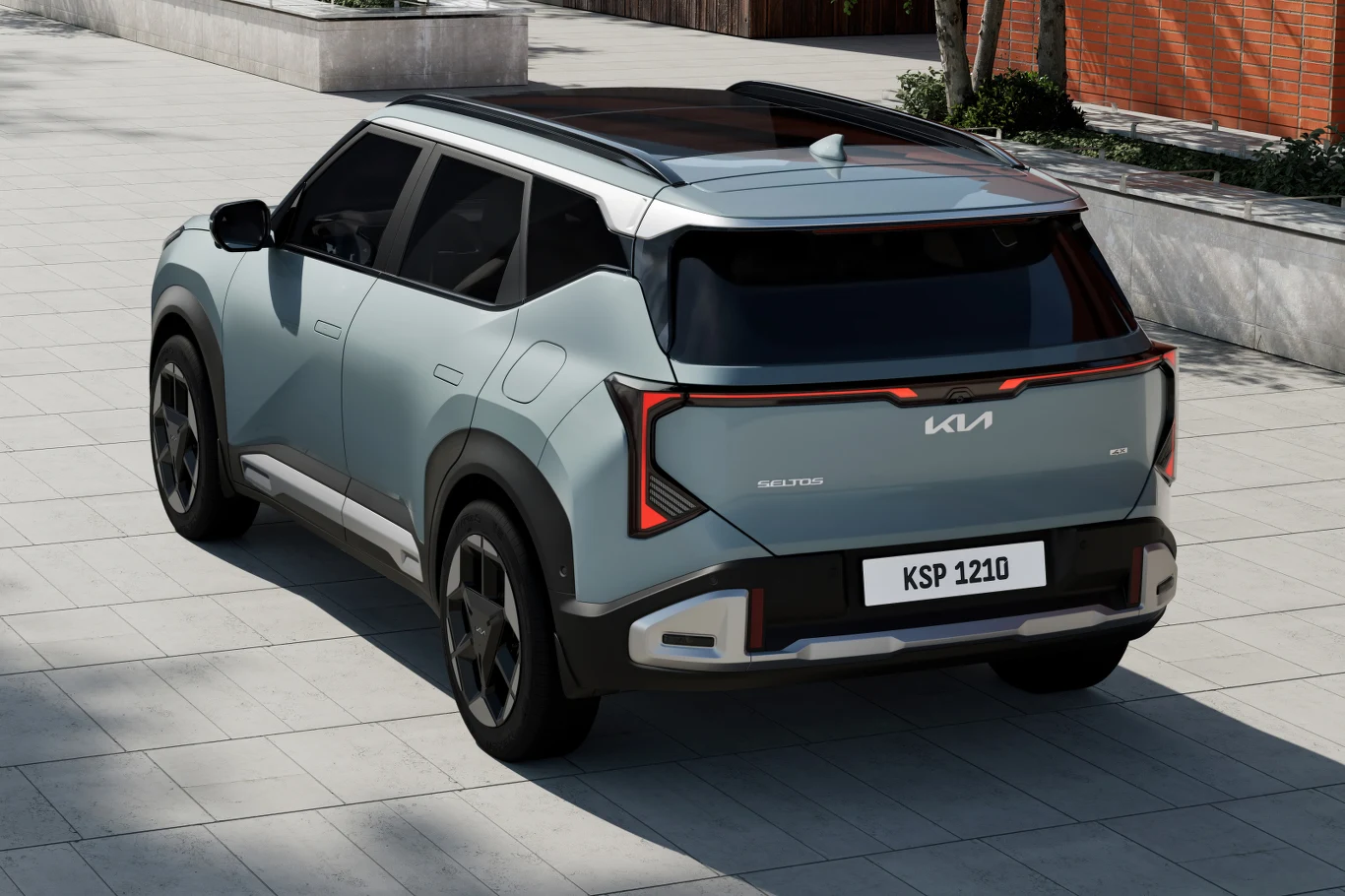 Pudełkowe nadwozie obiecuje większą przestrzeń. Bagażnik ma 536 litrów Nowoczesny SUV marki Kia o chromowanych detalach, panoramicznym dachu i charakterystycznych światłach tylnych zaparkowany na jasnym brukowanym placu w pobliżu ceglanego budynku.