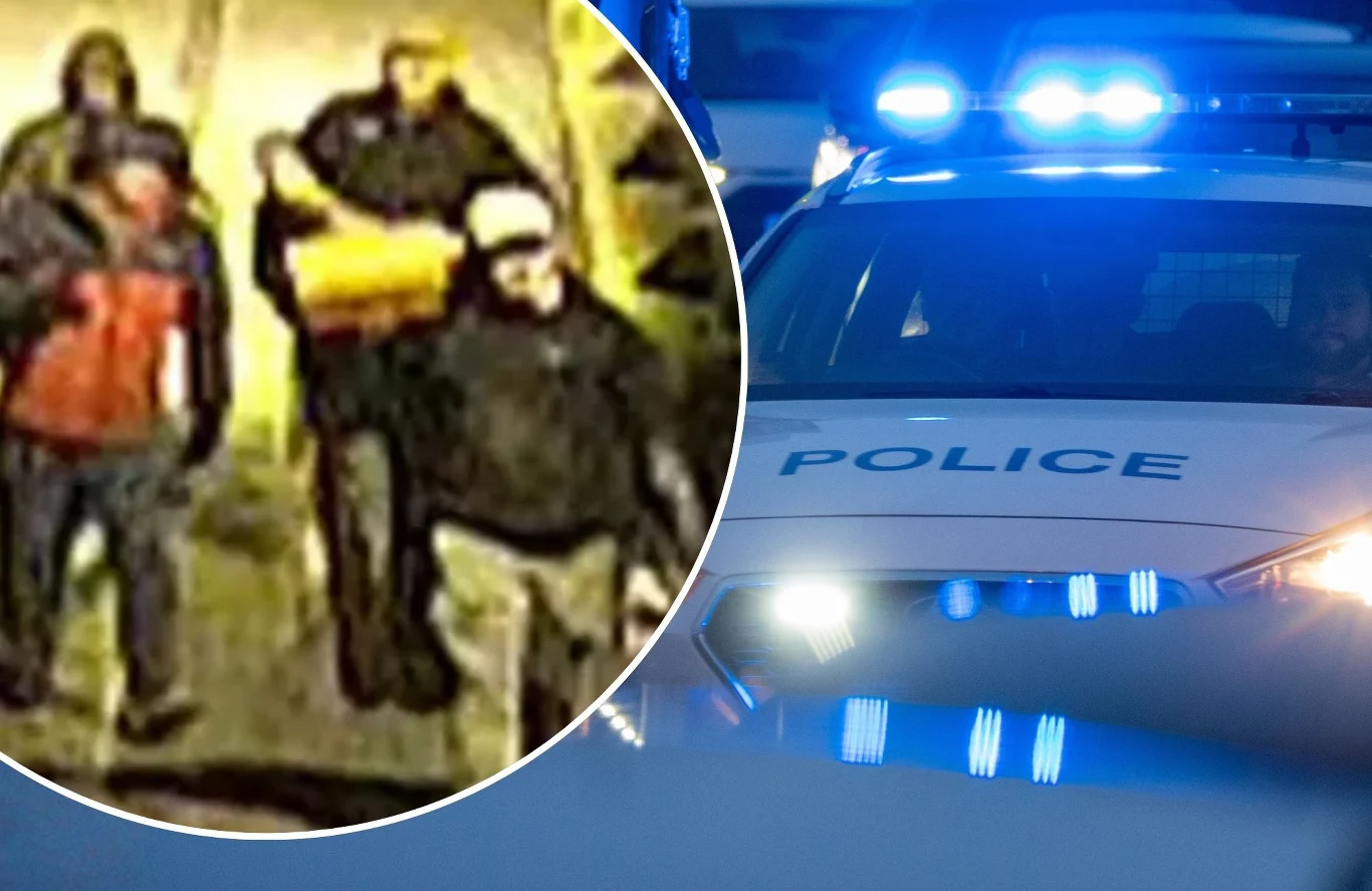 Napad na muzeum w Bristolu Grupa kilku osób idących chodnikiem nocą, ubrane w ciemne ubrania, jedna osoba niesie paczkę lub pojemnik, obok widoczne zbliżenie policyjnego radiowozu z włączonymi światłami na dachu.