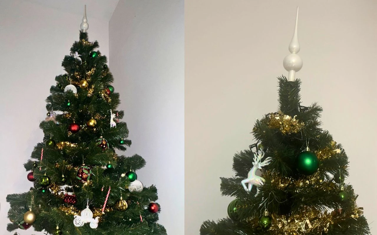 Choinka udekorowana kolorowymi bombkami, łańcuchami i ozdobami, na czubku znajduje się tradycyjna biała szpiczasta ozdoba.