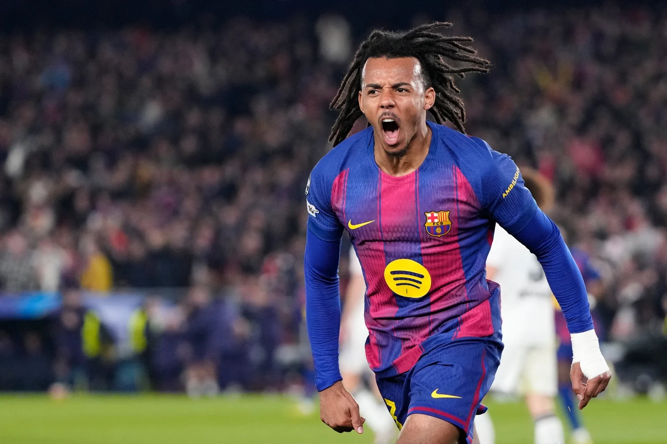 Piłkarz w stroju FC Barcelony biegnie po boisku z szeroko otwartymi ustami, wyrażając radość i ekscytację. Tłum kibiców w tle rozmyty, skupienie na sportowcu w dynamicznej pozie.