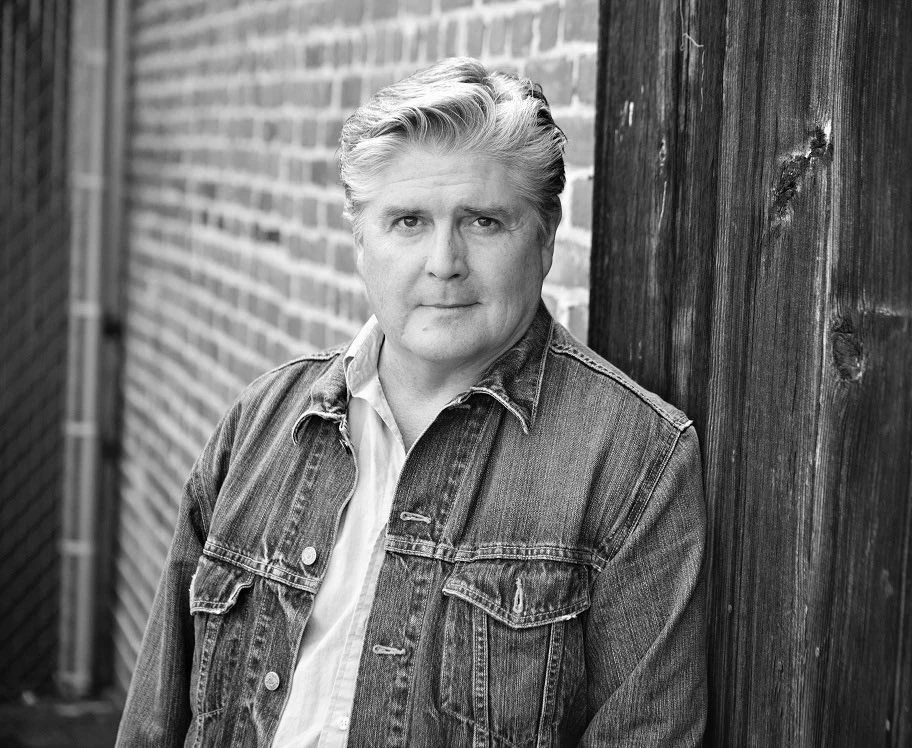 Jim Ward nie żyje. Był wybitnym aktorem głosowym Mężczyzna w średnim wieku o jasnych włosach stoi oparty o drewniany słup, obok ceglanej ściany, ubrany w dżinsową kurtkę i koszulę, patrzy spokojnie w stronę aparatu.