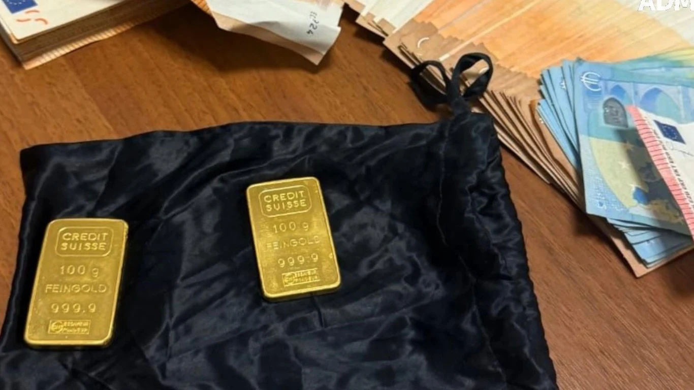 Polak zatrzymany na lotnisku w Bari. W bagażu ukrył złoto i 14 tys. euro Dwie sztabki złota na czarnym materiale obok ułożonych w stosy banknotów euro oraz dokumentów papierowych.