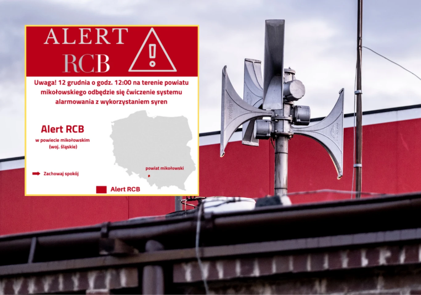 Alert RCB dla powiatu mikołowskiego. Chodzi o test systemu alarmowania Głośnik alarmowy zamontowany na dachu budynku, na tle czerwonej fasady, a w lewym górnym rogu plansza informacyjna o alertcie RCB dla powiatu mikołowskiego związana z próbą systemu alarmowania.