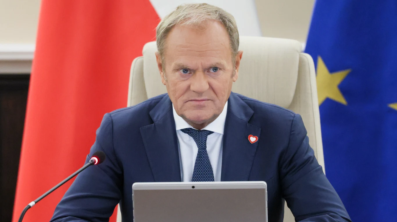 Niemal wszyscy ankietowani krytycznie wypowiedzieli się o współpracy premiera i prezydenta Mężczyzna w garniturze siedzi za biurkiem, na tle flag Polski oraz Unii Europejskiej, korzystając z laptopa podczas oficjalnego spotkania.