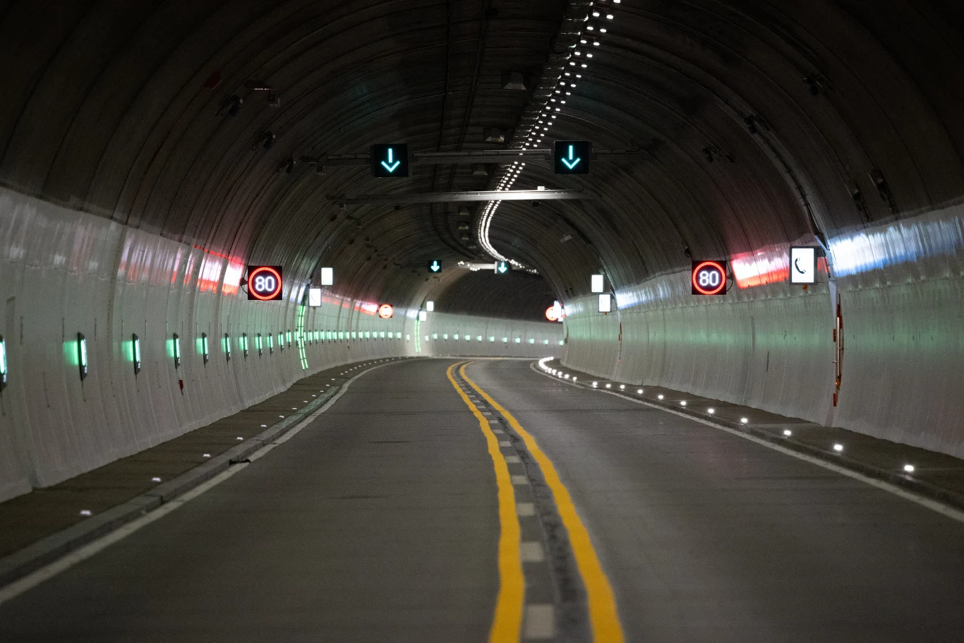 Utrudnienia na niemieckiej autostradzie A4. Na weekend zamkną tunel tuż za przejściem granicznym w Jędrzychowicach. Oświetlony tunel drogowy z dwiema żółtymi liniami pośrodku, ograniczeniem prędkości do 80 km/h i zielonymi strzałkami wskazującymi kierunek jazdy.
