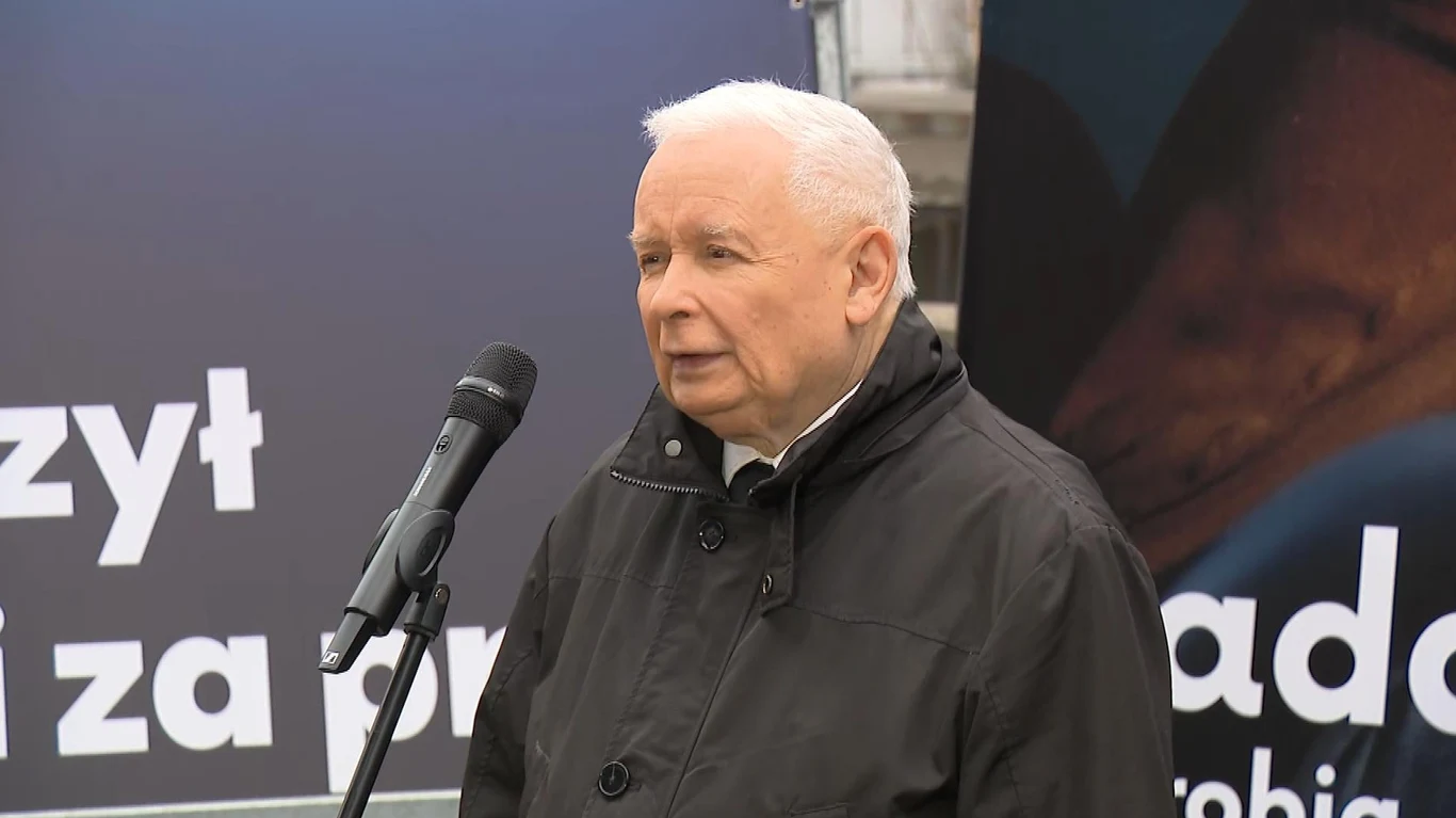 Jarosław Kaczyński przedstawił swoją ocenę rządu Donalda Tuska Starszy mężczyzna o jasnych włosach ubrany w ciemną kurtkę stoi przed mikrofonem, wypowiadając się publicznie na tle plansz z dużymi napisami.