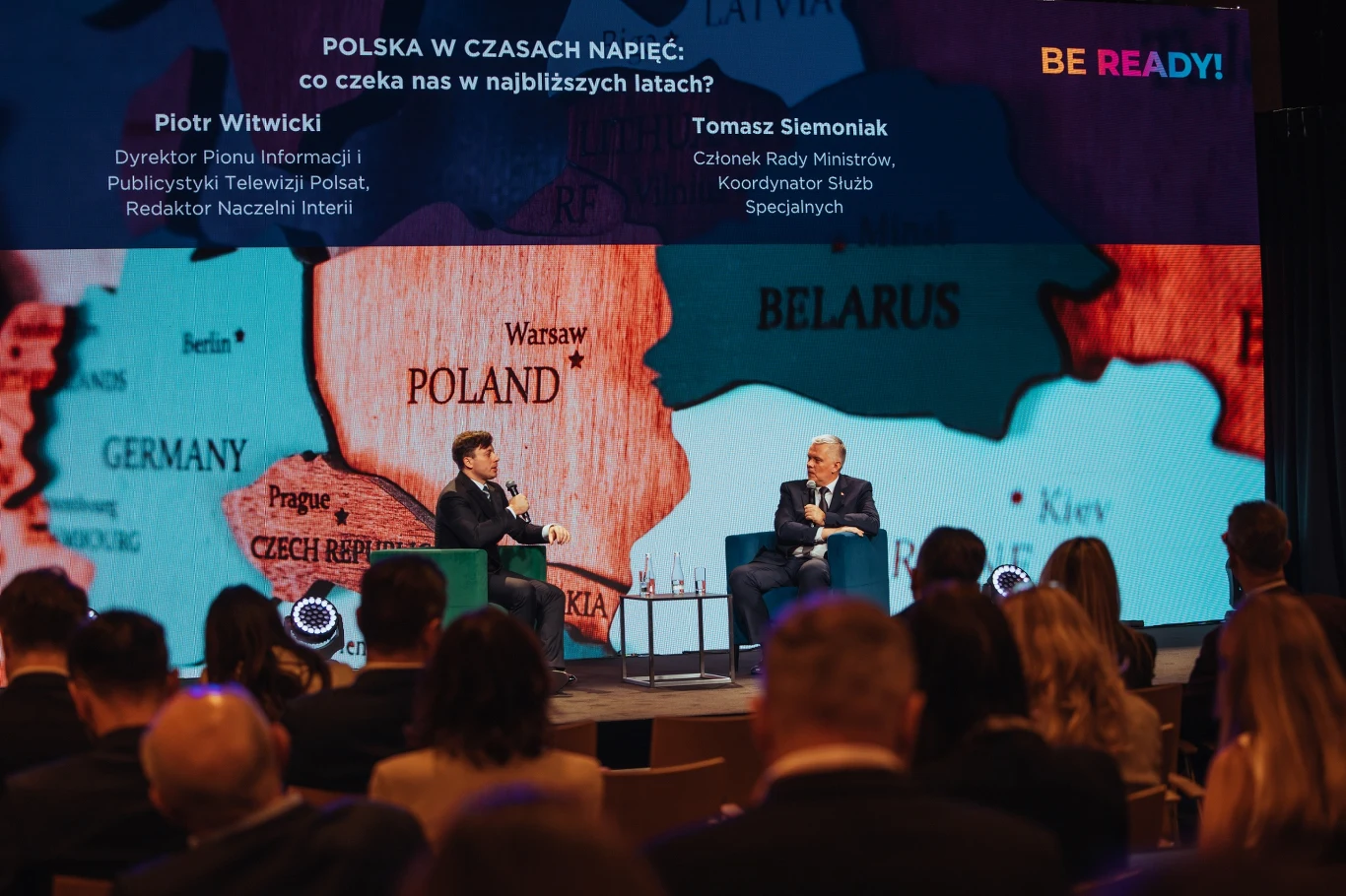 Debata z udziałem dwóch ekspertów siedzących na scenie przed dużą mapą Europy Środkowo-Wschodniej, w tle wyeksponowane jest terytorium Polski i krajów ościennych, przed sceną widoczni uczestnicy wydarzenia.