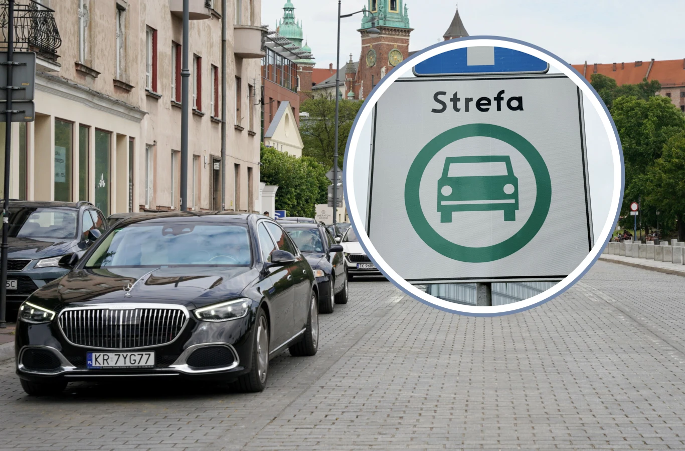 Strefa Czystego Transportu w Krakowie - co warto wiedzieć przed 1 stycznia? Czarny luksusowy samochód jedzie ulicą w mieście, obok wyeksponowany jest znak informujący o strefie wjazdu pojazdów, w tle widoczne budynki oraz zieleń.