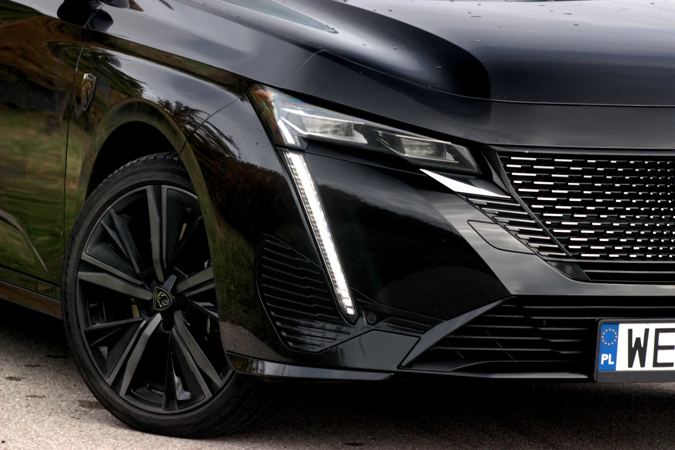 Czarny samochód z nowoczesnym reflektorem LED, charakterystyczną atrapą chłodnicy oraz polską tablicą rejestracyjną, widoczny fragment przedniego zderzaka i felga aluminiowa.
