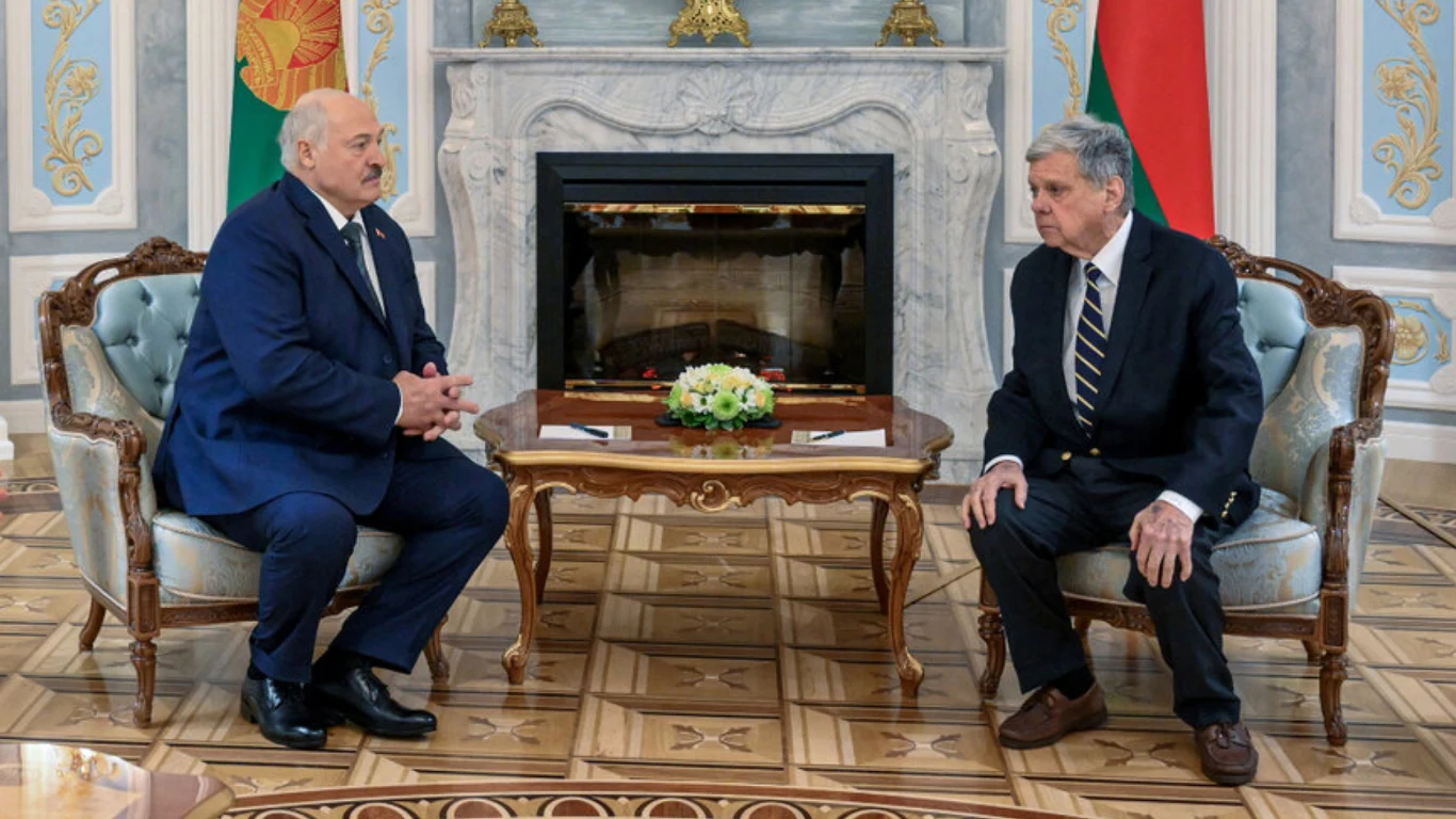Białoruś uwalnia więźniów dyplomatycznych (zdj. ilustracyjne) Dwóch mężczyzn siedzi naprzeciwko siebie na eleganckich fotelach w bogato zdobionym pomieszczeniu, pomiędzy nimi znajduje się stolik z kompozycją kwiatową, w tle marmurowy kominek oraz flagi.