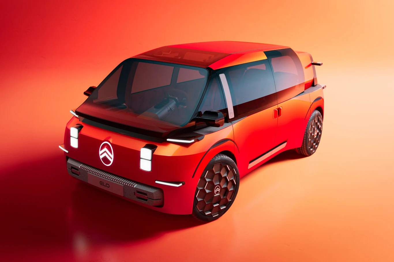 Citroen ELO to rozwinięcie projektu z 2022 r. zwanego OLI Koncepcyjny samochód marki Citroën w odważnym, nowoczesnym designie o czerwono-pomarńczowej karoserii, dużych przeszklonych powierzchniach i wyrazistych liniach nadwozia na jednolitym tle w ciepłych kolorach.