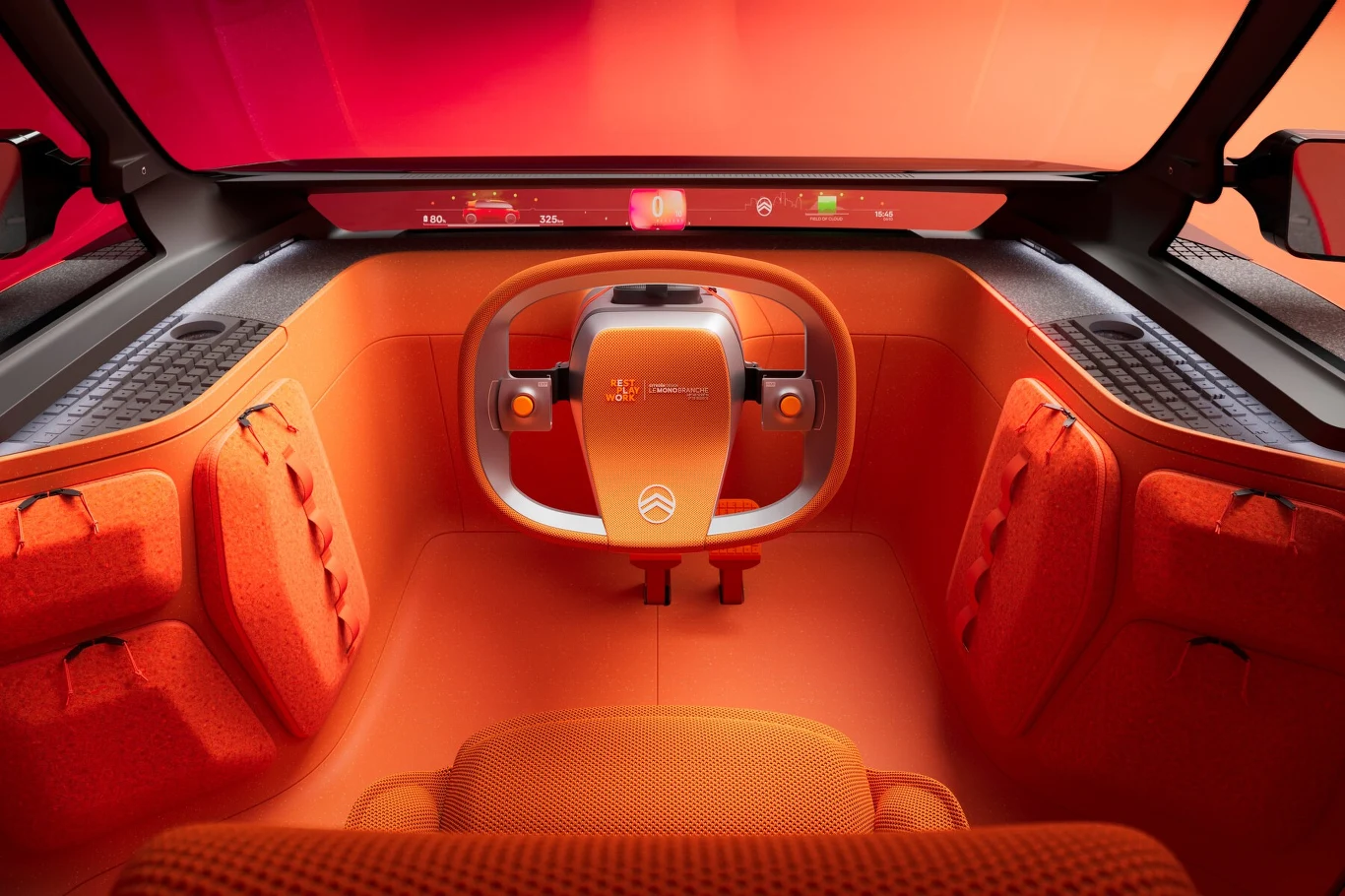 Kierownica przypomina tę z 70-letniego już DS'a Futurystyczna deska rozdzielcza samochodu koncepcyjnego Citroëna z pomarańczowym, minimalistycznym wnętrzem oraz nowoczesną kierownicą o nietypowym kształcie, otoczona jednolitym światłem i panelami z designerskimi wykończeniami.
