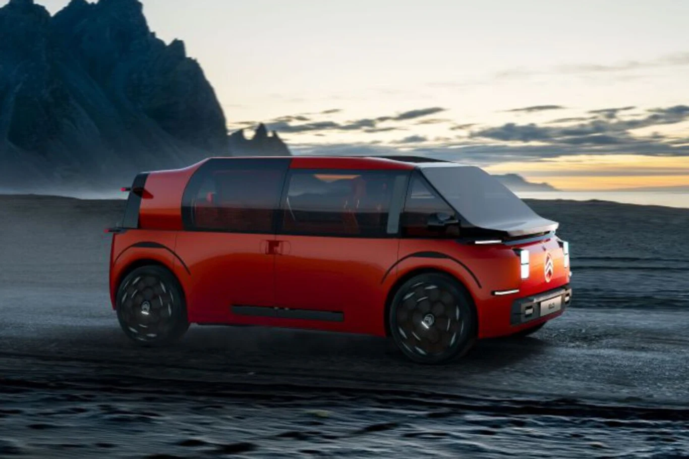 W teorii Citroen ELO to sześcioosobowy minivan Nowoczesny, czerwony samochód koncepcyjny poruszający się po ciemnej, kamienistej drodze przy brzegu morza, w tle góry i zachodzące słońce.