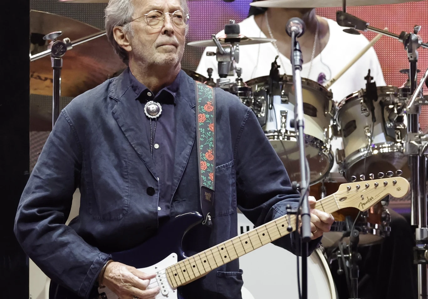 Eric Clapton nie pała sympatią do swojego kultowego hitu Muzyk grający na gitarze elektrycznej podczas koncertu, w tle widoczna perkusja i mikrofony sceniczne, scena oświetlona światłem koncertowym.