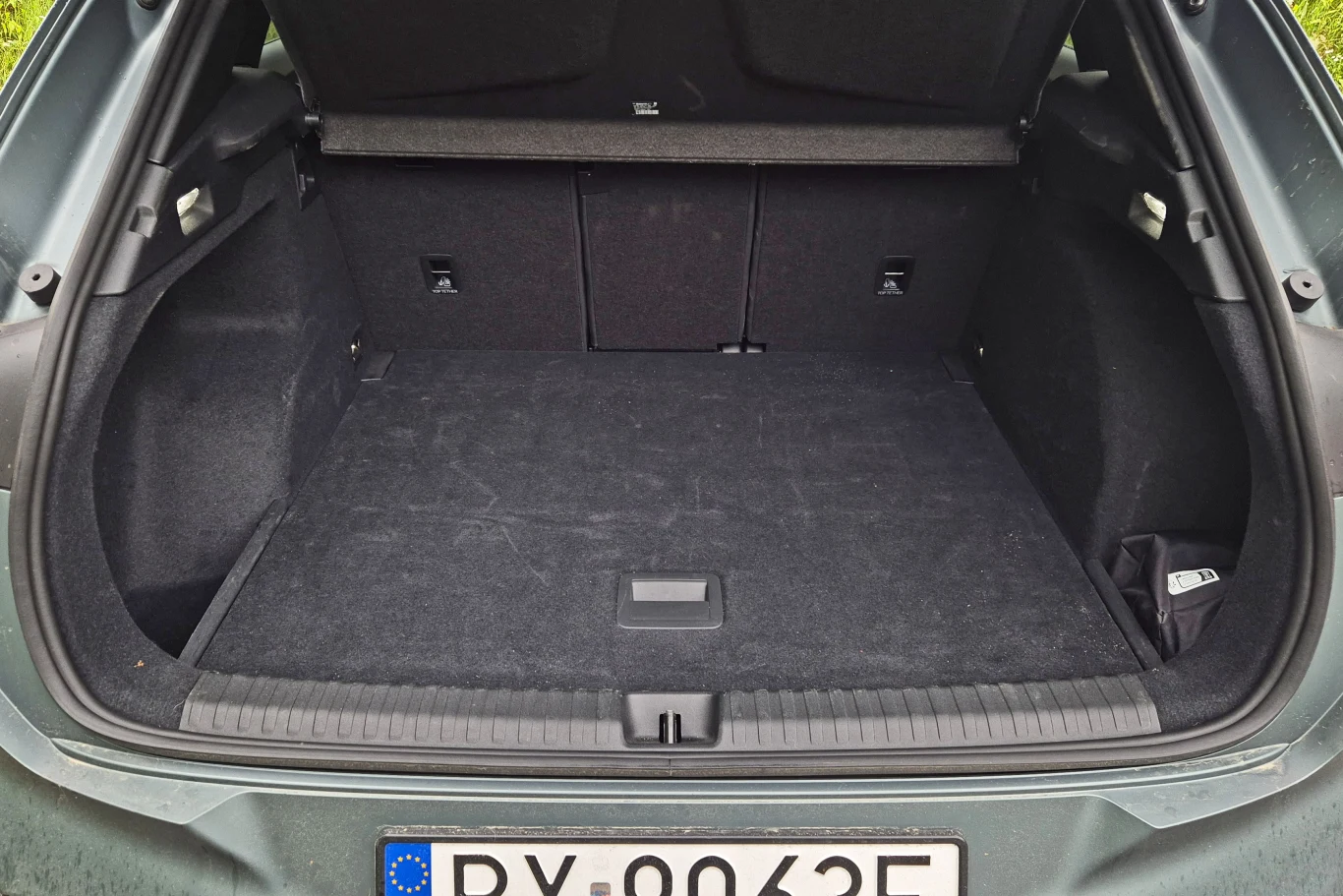 Otwarty bagażnik samochodu osobowego z widocznym numerem rejestracyjnym, przestronne i czyste wnętrze bagażnika, tapicerka w kolorze czarnym.