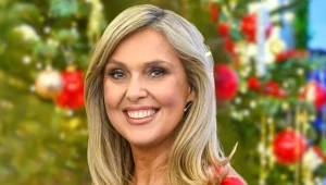 Ewa Wachowicz, uśmiechnięta, w czerwonym stroju, na tle choinki