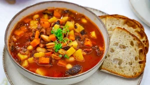 Zupa fasolowa z wędzoną śliwką, obok dwie kromki chleba