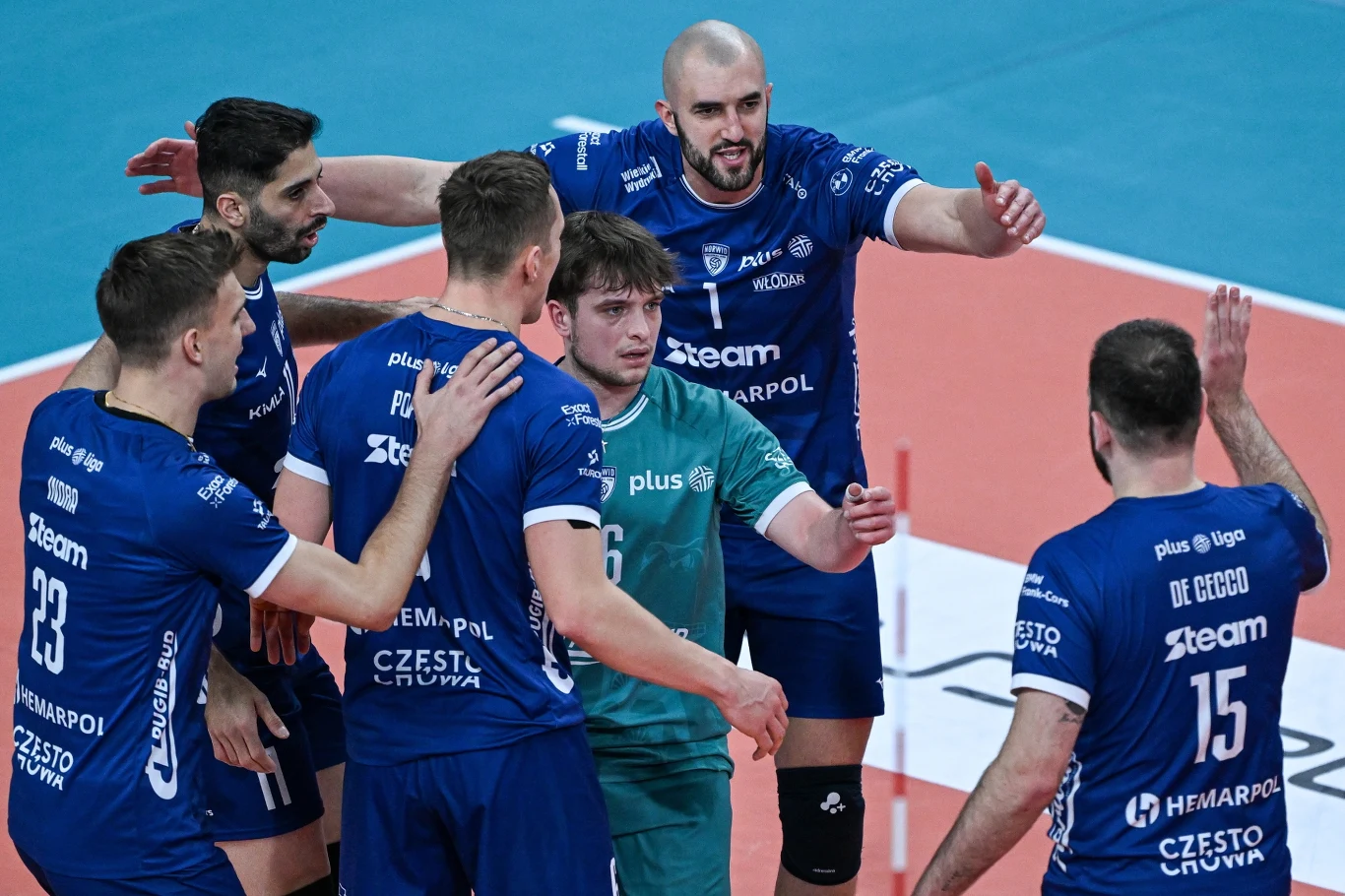 Siatkarze Steam Hemarpol Politechniki Częstochowa, z lewej Patrik Indra Grupa siatkarzy w niebieskich strojach świętuje punkt lub udaną akcję na boisku, obejmując się i wyrażając emocje zespołowe, w centrum znajduje się zawodnik w zielonej koszulce będący libero.