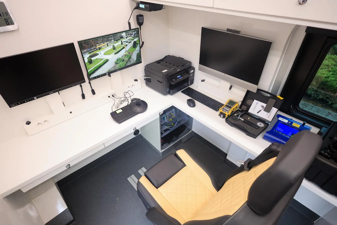 Wnętrze smogowozu Nowoczesne mobilne stanowisko pracy wyposażone w trzy monitory, drukarkę, klawiaturę, mysz, skaner dokumentów oraz wygodny fotel. Na biurku znajduje się również radiostacja i organizery na akcesoria biurowe.