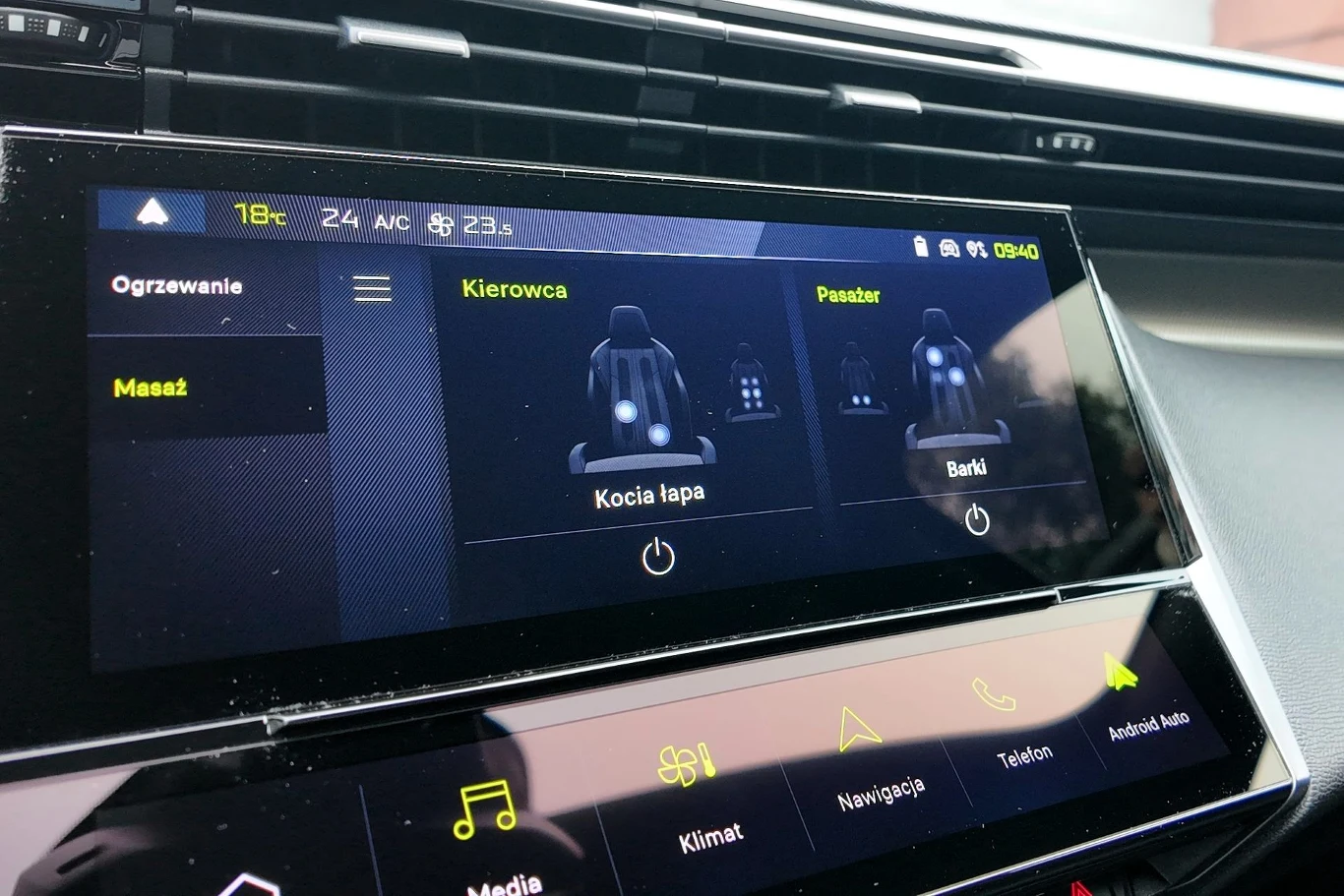 Funkcja masażu przednich foteli może uprzyjemnić oczekiwanie na uzupełnienie energii w akumulatorze. Kolorowy ekran dotykowy samochodowego systemu multimedialnego z widocznymi ustawieniami masażu foteli dla kierowcy i pasażera oraz ikonami nawigacji, mediów i klimatyzacji poniżej.