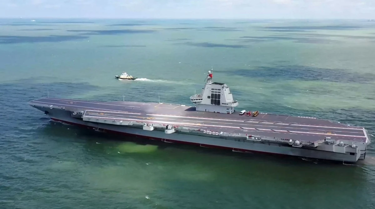 Chiński lotniskowiec Fujian przepłynął Cieśninę Tajwańską (zdj. ilustracyjne) Nowoczesny lotniskowiec na otwartym morzu, z pustym pokładem startowym. Obok jednostki widoczny jest niewielki statek towarzyszący, a powierzchnia morza jest spokojna.