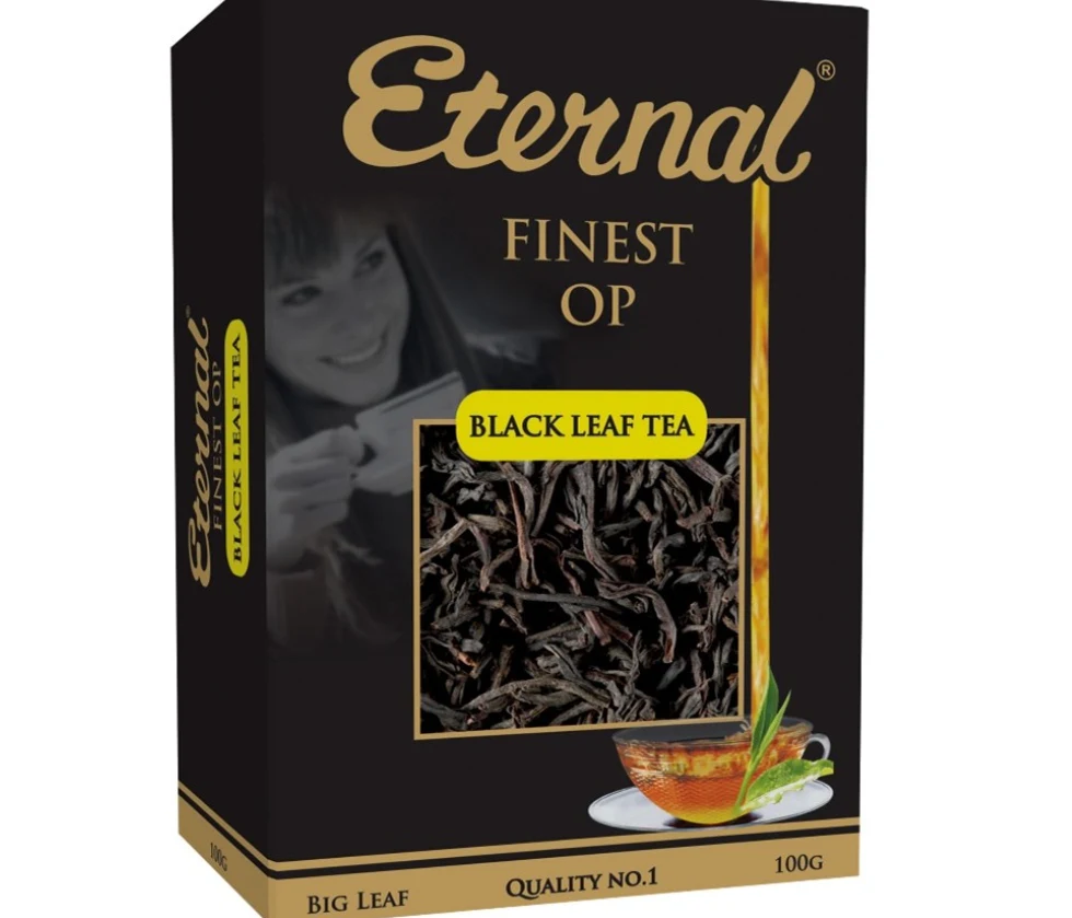 Opakowanie herbaty czarnej marki Eternal z widoczną nazwą produktu i grafiką liści herbaty, obok szklanki z parzoną herbatą i listkiem oraz cytryną, w tle kobieta pijąca herbatę.