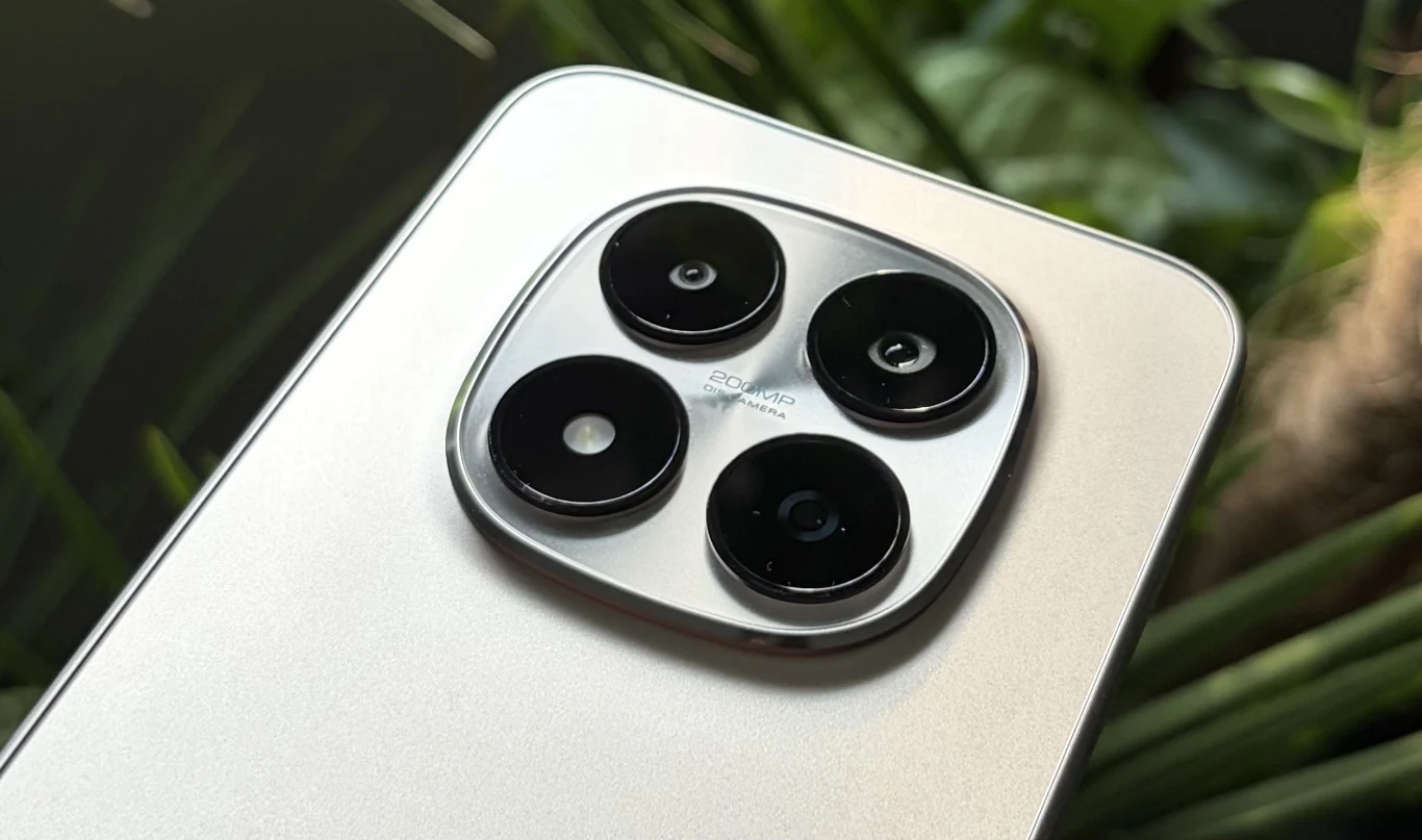 Cztery kamery umieszczone w kwadratowym module na srebrnej obudowie nowoczesnego smartfona z wyraźnym napisem 50MP, w tle liście roślin.