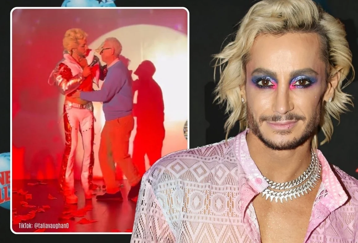 Osoba z makijażem i fryzurą stylizowaną na blond włosy, ubrana w jasnoróżową, ażurową koszulę i naszyjnik, znajduje się na pierwszym planie. W tle widać scenę w kolorowym oświetleniu, gdzie jedna z osób ubrana jest w błyszczący, ekstrawagancki strój i ...