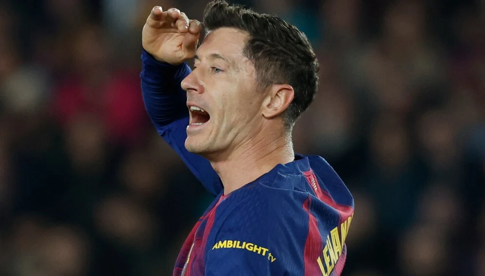 Piłkarz w koszulce w barwach klubu FC Barcelona unosi rękę do czoła i patrzy przed siebie, otwierając usta jakby dawał wskazówki lub wołał do kogoś podczas meczu, w tle rozmyta publiczność stadionu.