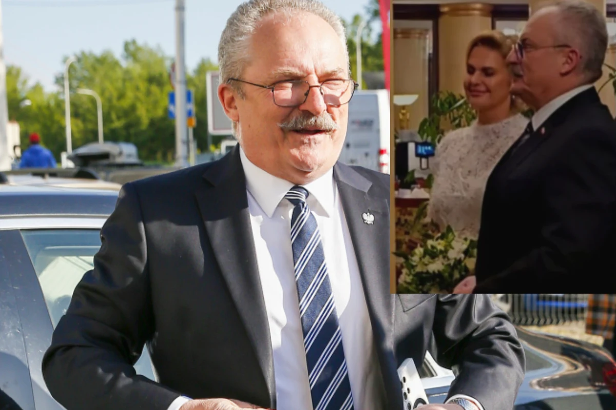 Marek Jakubiak, fot. Facebook: Marek Jakubiak Mężczyzna w średnim wieku w garniturze, z wąsami i okularami, stoi przy samochodzie na tle miejskiej ulicy. W prawym górnym rogu znajduje się wstawka z uroczystości – uśmiechnięta kobieta w sukni ślubnej oraz mężczyzna w marynarce, oboje w eleganckich ...