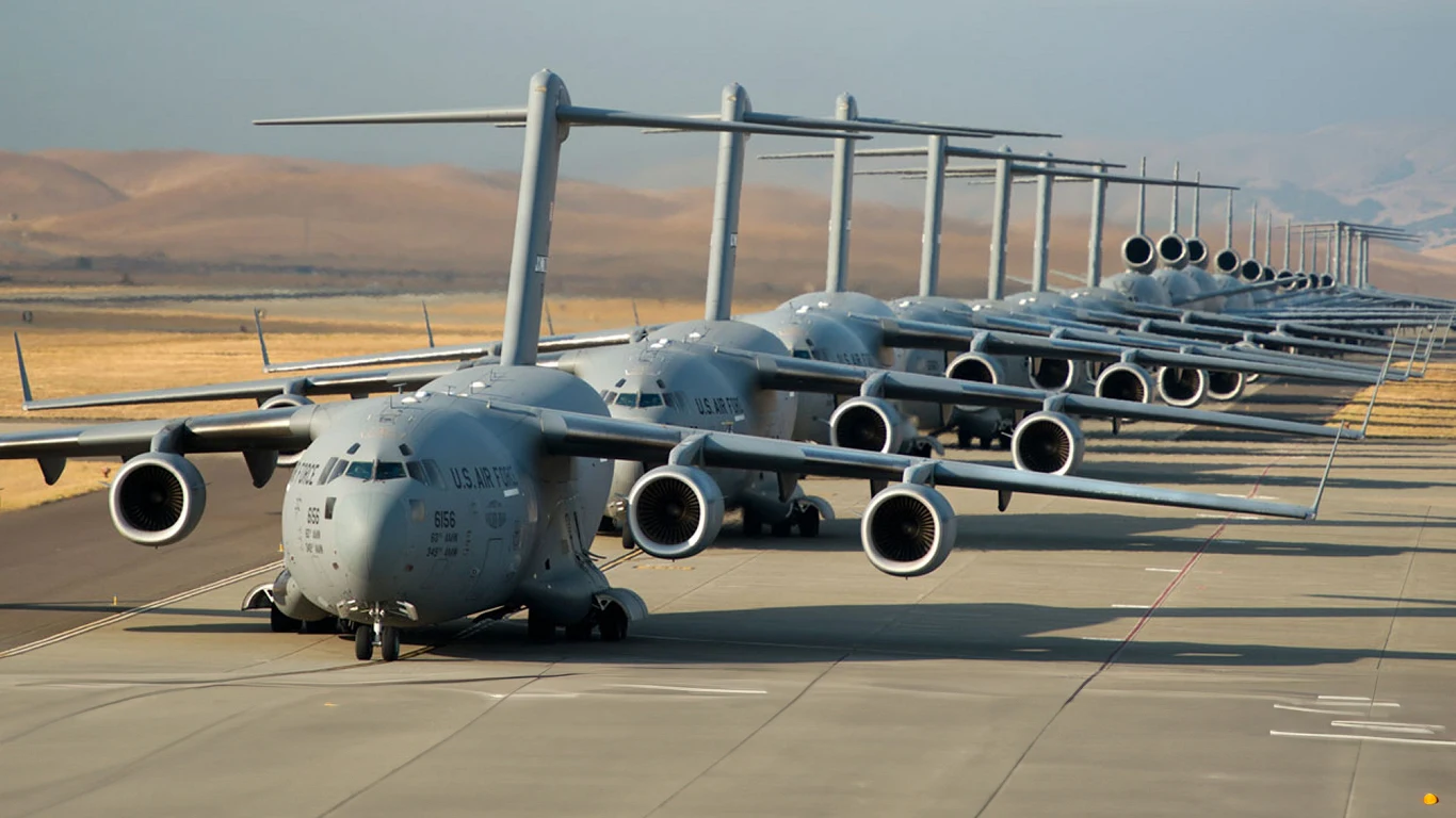 Polska eksportuje na świat coraz więcej broni Szereg wojskowych samolotów transportowych typu C-17 Globemaster III zaparkowanych na płycie lotniska, ustawionych równolegle do siebie, z widoczną pustynną scenerią w tle.