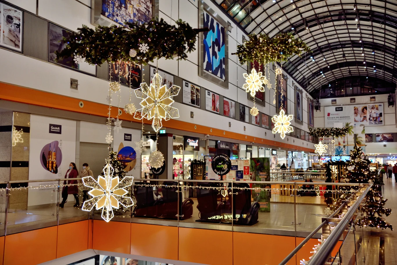 Szef PIP: Sprawdzimy, czy Wigilia była dniem wolnym od pracy Galeria handlowa udekorowana świątecznymi girlandami, lampkami i dużymi świetlnymi gwiazdami, widoczne sklepy i choinki, korytarz z przechodzącymi ludźmi oraz ozdobami wiszącymi pod sufitem.