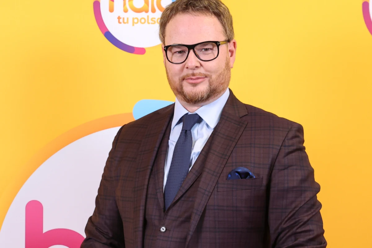 Jan Lubomirski-Lanckoroński Jan Lubomirski-Lanckoroński w eleganckim, brązowym garniturze pozuje na tle ścianki z logo.