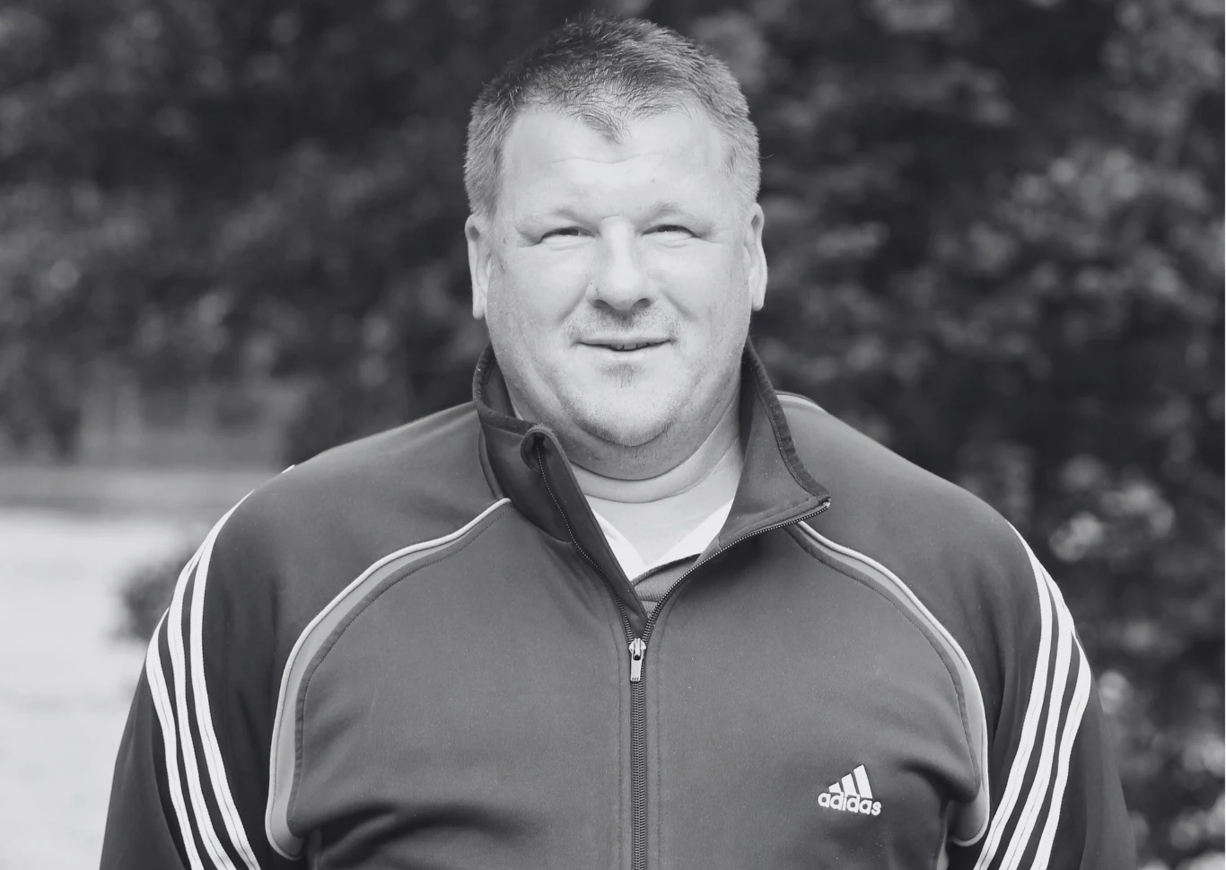 W wieku 60 lat zmarł Maciej Łasicki, brązowy medalista Igrzysk Olimpijskich w Barcelonie Mężczyzna w średnim wieku ubrany w ciemną sportową kurtkę z suwakiem oraz charakterystycznym logo marki adidas, stoi na świeżym powietrzu przed rozmytym tłem z zielenią.