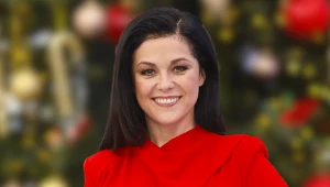 Uśmiechnięta Kasia Cichopek w czerwonej sukience na tle choinki