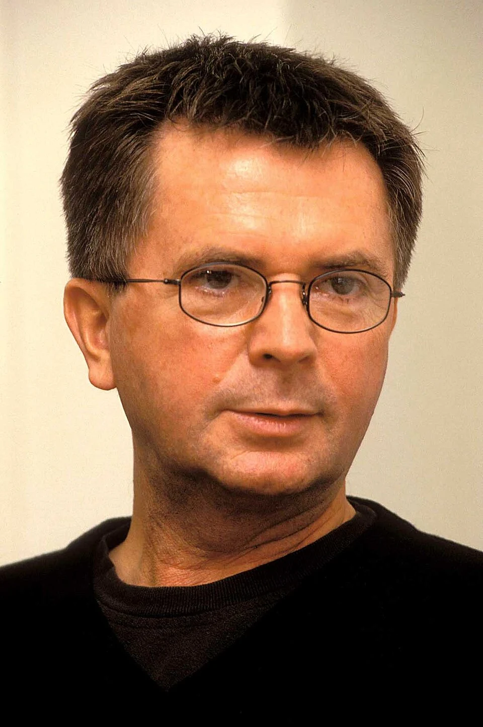 Aleksander Wolszczan (2007 r.). Mężczyzna o krótkich ciemnych włosach i delikatnym zaroście, noszący okulary w cienkich oprawkach, ubrany w ciemny sweter. Tło jednolite, jasne, neutralne.