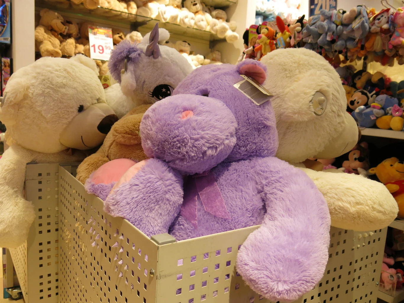 Misia pluszowego za 4200 funtów (około 20,2 tys. zł) oferuje przed świętami słynny londyński dom towarowy Harrods (zdj. ilustracyjne) Pluszowe maskotki różnego rodzaju, w tym duży fioletowy hipopotam oraz białe misie, ustawione w metalowym koszu w sklepie z zabawkami. W tle widać więcej zabawek i półki pełne pluszaków.