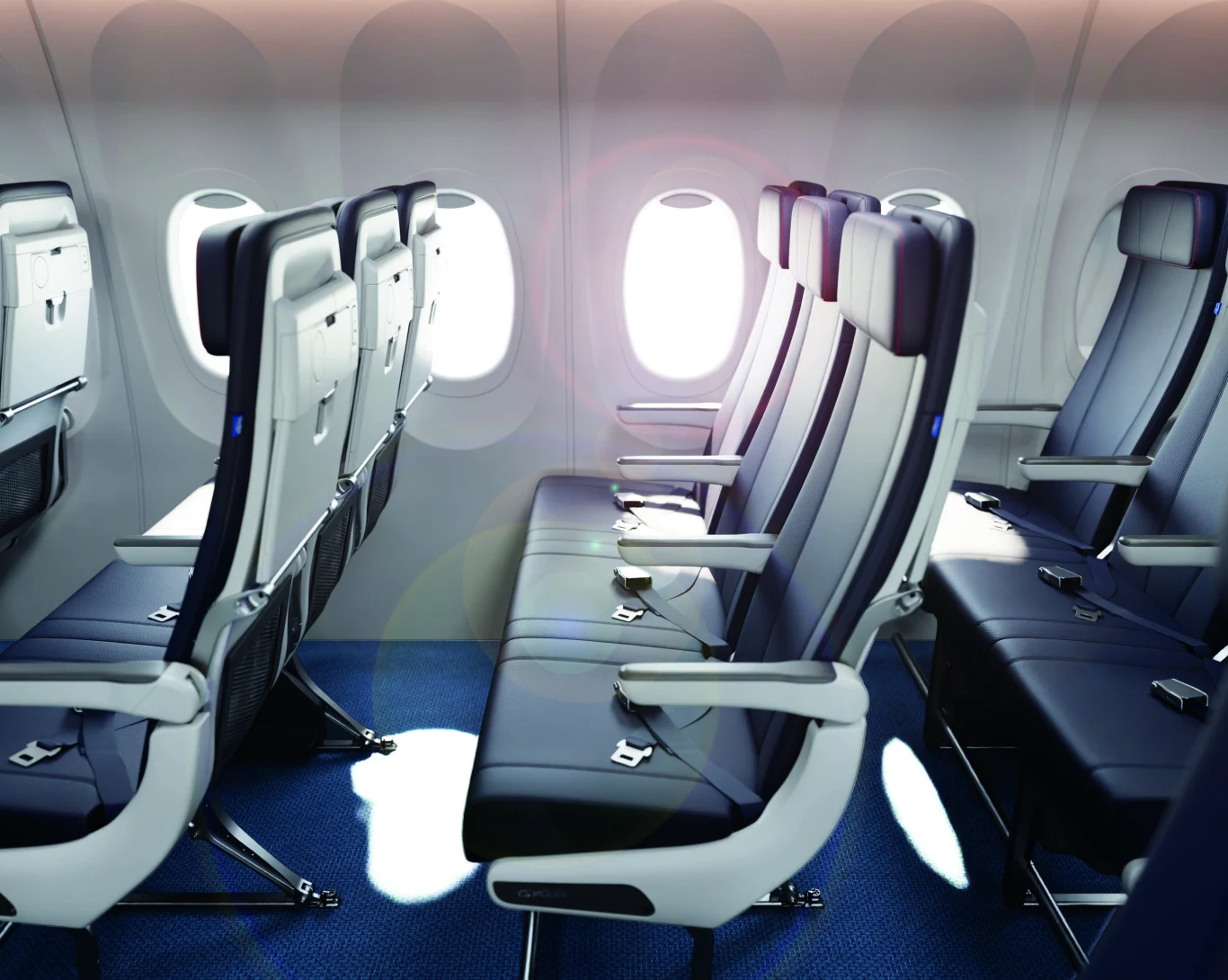 Rząd trzech pustych foteli w klasie ekonomicznej samolotu pasażerskiego, jasne światło wpadające przez okna po lewej stronie, podłoga pokryta niebieską wykładziną, widoczne pasy bezpieczeństwa i podłokietniki.