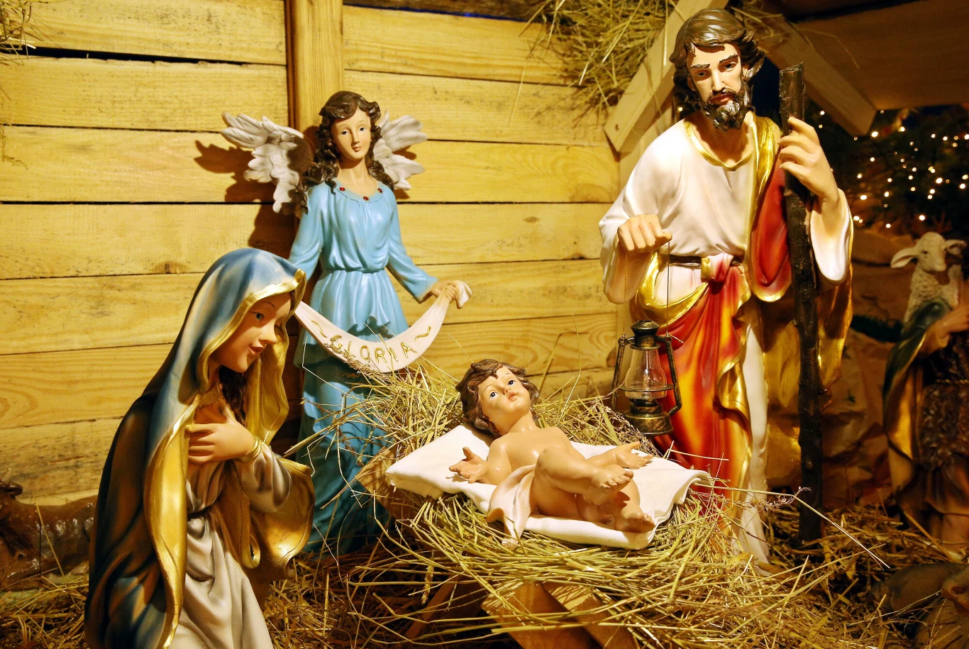 Szopka bożonarodzeniowa Szopka bożonarodzeniowa z figurami Maryi, Józefa i Dzieciątka Jezus, a także anioła w tle, wszystko ustawione w drewnianej stajence, na podłożu ze słomy.