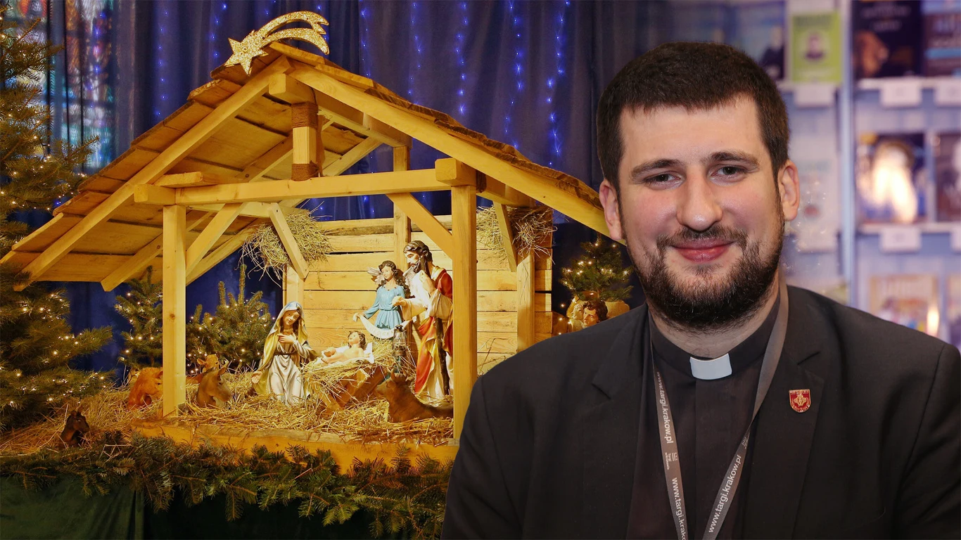 Ksiądz Krzysztof Porosło opowiada o tajemnicach Bożego Narodzenia Kapłan uśmiechnięty stoi na tle szopki bożonarodzeniowej wykonanej z drewna, ozdobionej figurami Świętej Rodziny, Trzech Króli oraz zwierząt, przy dekoracyjnych choinkach oświetlonych delikatnymi lampkami.